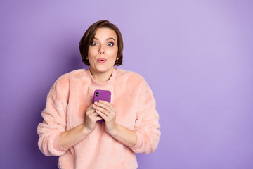 Photo of funny blogger lady holding telephone hands check blog enjoy many new followers subscribers wear casual stylish pink pullover isolated purple color background