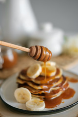 delicious American pancakes with bananas and honey on the plate for a breakfast. selective focus. Scandinavian style kitchen. 