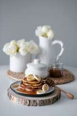 delicious American pancakes with bananas and honey on the plate for a breakfast. selective focus. Scandinavian style kitchen. 
