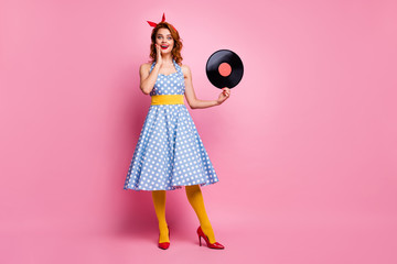 Full size photo of pretty amazed lady hold old fashion classic vinyl cd retro theme party collection single wear dotted dress high-heels yellow tights isolated pink color background