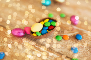 easter, sweets and confectionery concept - close up of chocolate egg and candy drops on wooden table