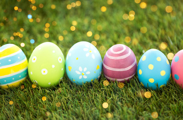 easter, holidays and tradition concept - row of colored eggs on artificial grass