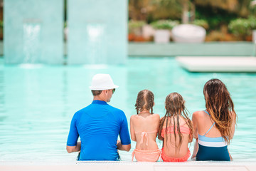 Obraz premium Happy family of four in outdoors swimming pool