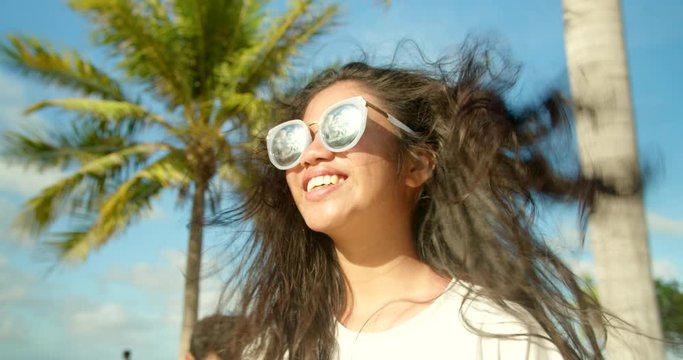 Beautiful Tropical Filipina Girl Fixing Hair Blown By the Wind Beside Palm Trees
