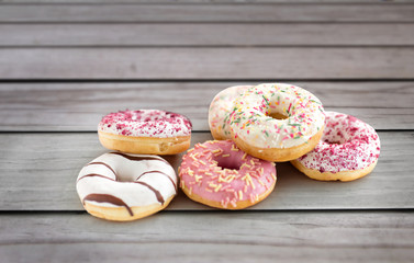 sweet food, junk-food and unhealthy eating concept - close up of glazed donuts over grey wooden boards background
