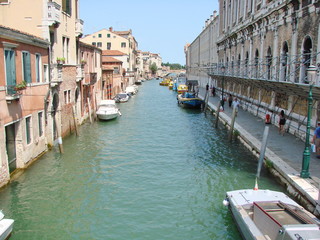 Fototapeta na wymiar The unique landscape of the narrow waterways of sunny Venice, connected by small numerous bridges.