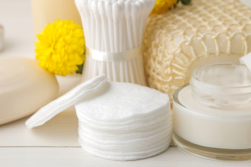 Various personal care products. Cotton pads close-up and sticks and yellow flowers on a white...