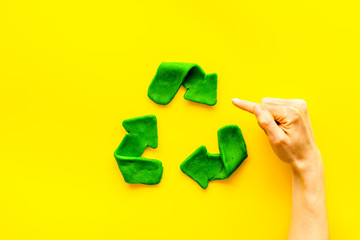 Recycling symbol - composition with hands - on yellow background top-down copy space