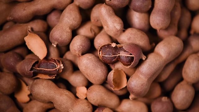 Sweet tamarind on rotating background. Top view. Exotic fruit, tropical palm branch. Vegan and raw food concept