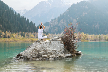 Young zen man in meditation. Outdoor yoga in mountain lake. Exercise Agni Stambhasana.
