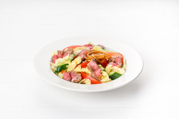 Salad in a white plate with roast beef, fresh cucumber, pepper.