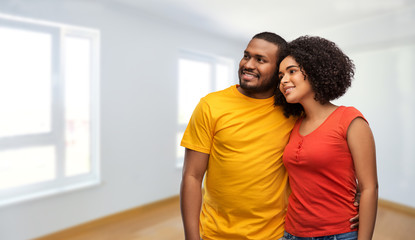 new home, real estate and people concept - happy african american couple hugging over empty apartment on background