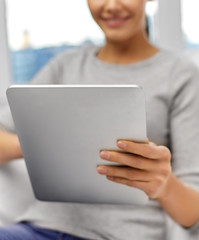technology, leisure and people concept - close up of woman with tablet pc computer sitting on sofa at home
