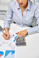 business, finances and accounting concept - close up of businesswoman counting on calculator and...