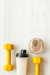 Obraz na płótnie Canvas Sport diet. Protein shake near dumbbells on white background top-down flat lay copy space