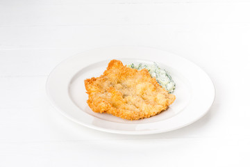 In a white plate, a piece of fried fish.