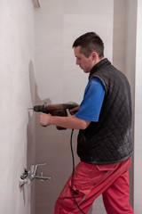 construction worker drilling holes in the bathroom