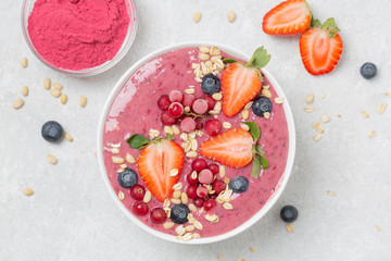 Healthy breakfast bowl: berry smoothie with banana, strawberries, blueberries, red currants, granola and acai berry powder.