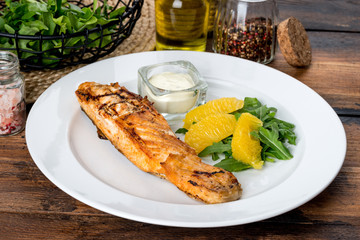 In a white plate, a piece of fried fish with sauce and lemon.