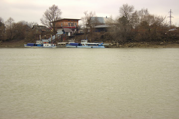 Small river pier with boats. View from the opposite shore
