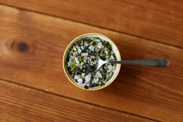food, culinary and unhealthy eating concept - close up of flavored sea salt in bowl with spoon on wooden table