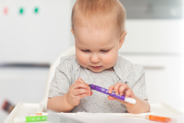 Cute baby paint using colorful pencils on white table