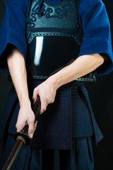 Hands with a wooden sword. Swordsman in uniform. Kendo fighter