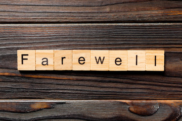 farewell word written on wood block. farewell text on table, concept