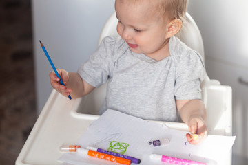 Cute baby paint using colorful pencils on white table