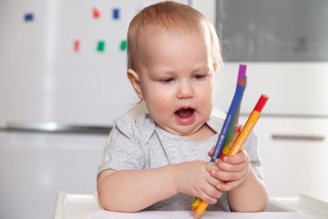 Cute baby paint using colorful pencils on white table