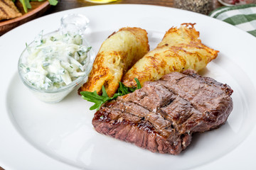 In a white plate steak with pancakes and sauce