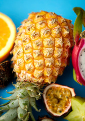 food and healthy eating concept - close up of pineapple with other exotic fruits on blue background