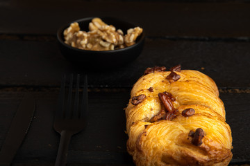 small puff pastry cake with nuts on black wooden background