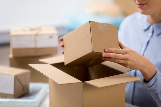 delivery, mail service, people and shipment concept - close up of woman packing parcel box at post office
