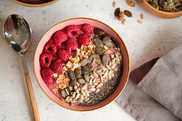 Healthy food - smoothie bowl topped with raspberries, granola, seeds and chia. Closeup view