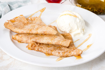 On a white plate are pancakes with creamy ice cream.