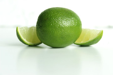 whole and half with slice of fresh green lime on white background