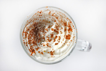 A view of a cappuccino in a cup, shot from above. The cup shows cream in the cup
