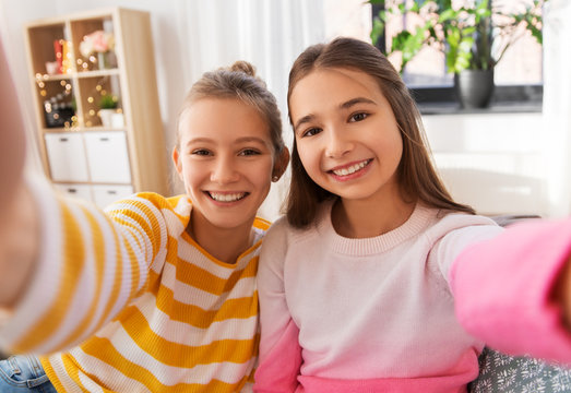 people and friendship concept - happy smiling teenage girls taking selfie at home