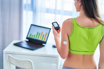 Woman diabetics control and checking glucose level with a remote sensor. Online continuous monitoring glucose levels without blood. Medical technology in diabetes treatment