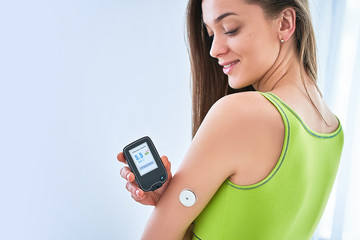 Woman diabetics control and checking glucose level with a remote sensor. Continuous monitoring glucose levels without blood. Medical technology in sugar diabetes treatment - obrazy, fototapety, plakaty