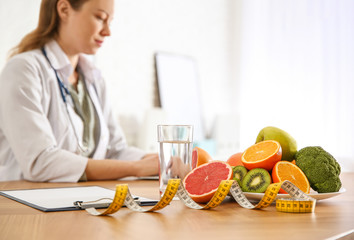 Healthy products, measuring tape and blurred nutritionist on background