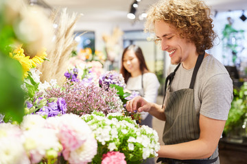 Man as a florist maintains cut flowers assortment