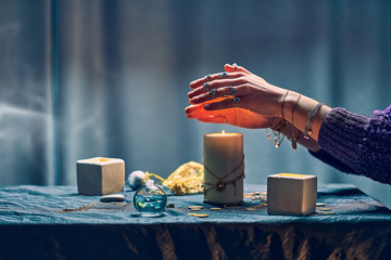 Witch woman using candles flame for magic spell during mystical witchcraft and divination