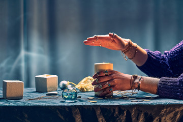 Gypsy witch woman using candles flame for magic spell during mystical witchcraft