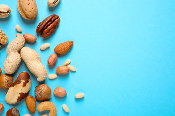 Fototapeta na wymiar Different delicious nuts on light blue background, flat lay. Space for text