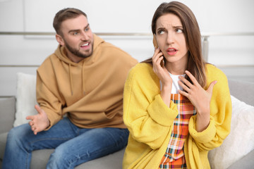 Woman with smartphone ignoring her boyfriend at home. Relationship problems