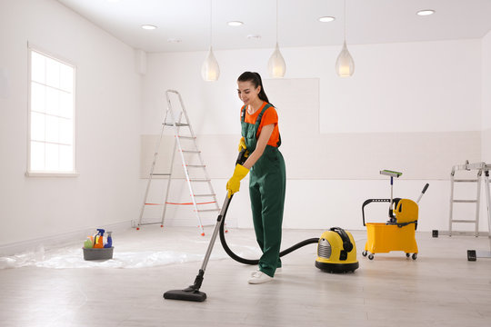 Professional janitor cleaning room with vacuum after renovation