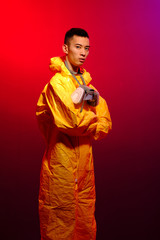 Asian man in a yellow suit of chemical protection and in a protective mask on a color trend color background. Concept Breaking Bad