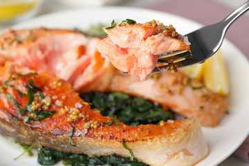 Tasty salmon with spinach on plate, closeup